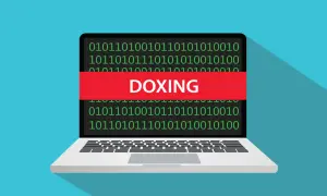 Portátil con código binario y una banda roja que dice "DOXING", ilustrando el doxeo que es.