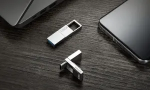 Dos unidades USB plateadas, una de 128GB y otra con logo Xiaomi, junto a un portátil y un smartphone. Perfectas para tus aplicaciones portables.
