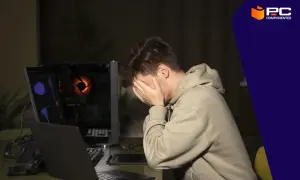 Joven frustrado con su ordenador que va muy lento. La pantalla muestra gráficos complejos y el ventilador de la torre brilla con luz naranja.
