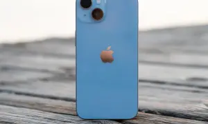 Un iPhone 14 azul descansa sobre madera. ¿Cuánto mide el iPhone 14? Sus dimensiones son perfectas para tu mano.