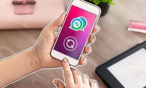 Mano sujetando un smartphone con un icono de chat y un símbolo de actualización, indicando cómo actualizar una app.