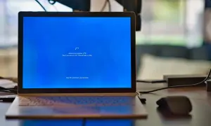 Un ordenador portátil muestra una pantalla azul de Windows con el mensaje "Working on updates 27%". El proceso de formatear ordenador está en marcha.