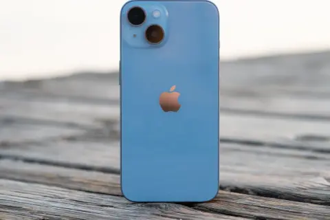 Un iPhone 14 azul descansa sobre madera. ¿Cuánto mide el iPhone 14? Sus dimensiones son perfectas para tu mano.