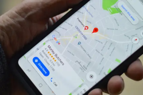 Mano sujetando un móvil con Google Maps. Si te preguntas como saber si me rastrean el móvil, revisa tu ubicación.