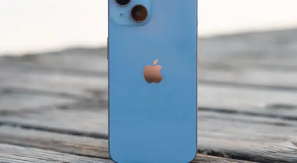 Un iPhone 14 azul descansa sobre madera. ¿Cuánto mide el iPhone 14? Sus dimensiones son perfectas para tu mano.