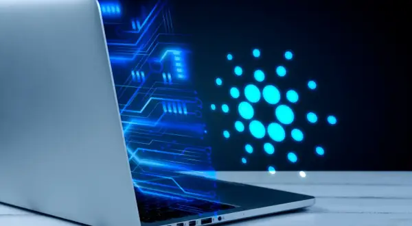 Un portátil muestra un diseño de circuito azul brillante y el logo de Cardano, ilustrando cómo funciona una máquina virtual en un entorno digital.