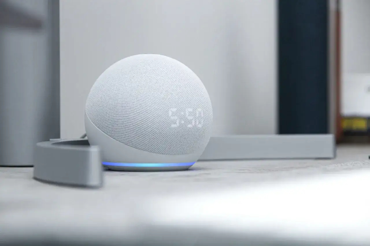 Altavoz inteligente blanco con pantalla LED mostrando la hora. La luz azul indica que est&aacute; listo para recibir comandos de Alexa.