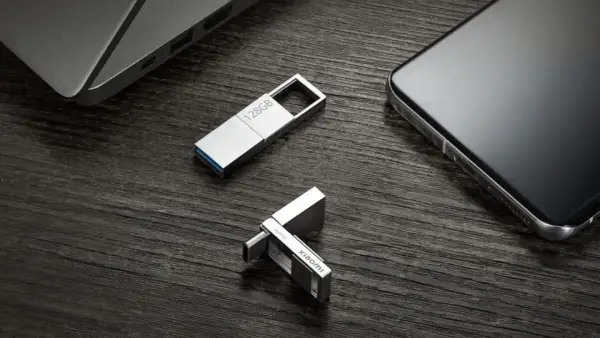 Dos unidades USB plateadas, una de 128GB y otra con logo Xiaomi, junto a un portátil y un smartphone. Perfectas para tus aplicaciones portables.