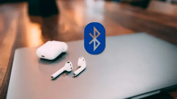 Auriculares inalámbricos y el logo de Bluetooth sobre un portátil. Guía para conectar auriculares bluetooth a pc.